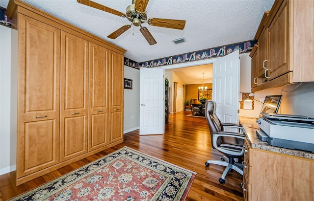 office area with ceiling fan with notable chandelier, dark hardwood / wood-style flooring, and a textured ceiling