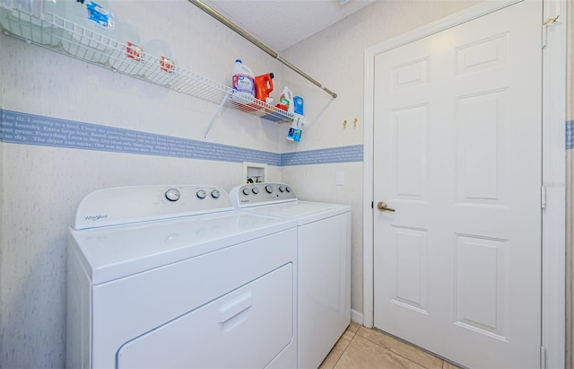 laundry area featuring washing machine and dryer, light tile patterned floors, and a textured ceiling