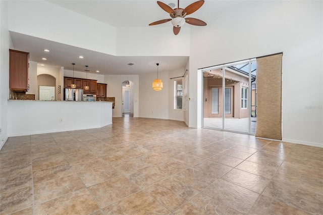 unfurnished living room with ceiling fan and a high ceiling