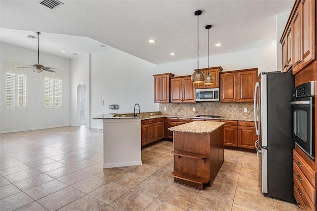 kitchen with a center island, decorative backsplash, appliances with stainless steel finishes, decorative light fixtures, and kitchen peninsula