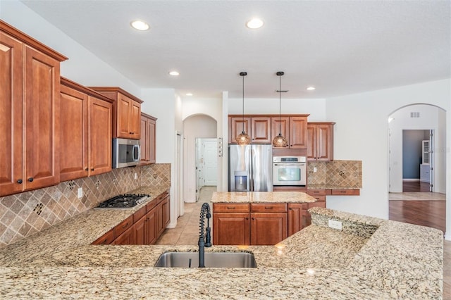 kitchen with backsplash, sink, stainless steel appliances, and decorative light fixtures