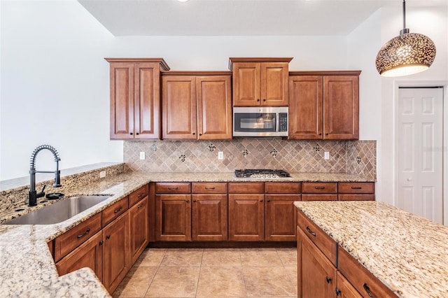 kitchen featuring light stone countertops, sink, pendant lighting, decorative backsplash, and appliances with stainless steel finishes