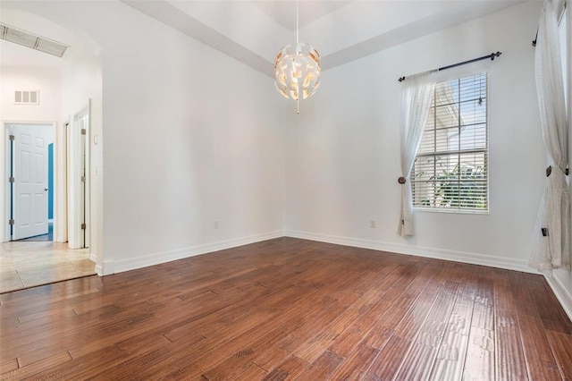 empty room featuring a chandelier and hardwood / wood-style floors