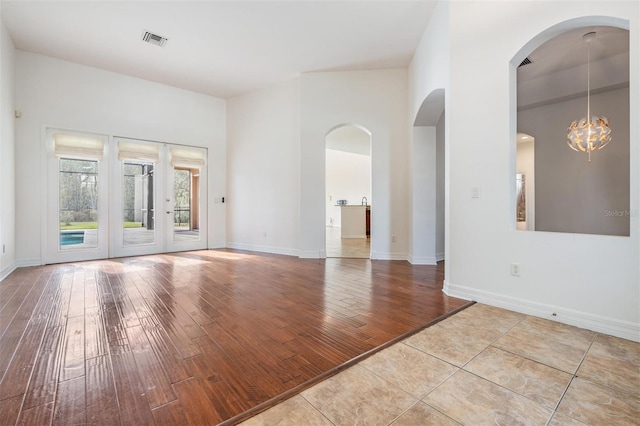 unfurnished room with a chandelier, light hardwood / wood-style flooring, and french doors