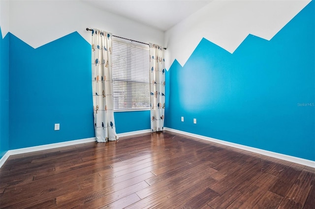 spare room with dark hardwood / wood-style floors and vaulted ceiling