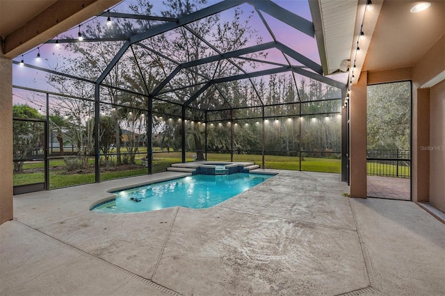 pool at dusk with glass enclosure, an in ground hot tub, a yard, and a patio