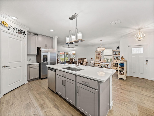 kitchen with gray cabinetry, a center island with sink, appliances with stainless steel finishes, and sink