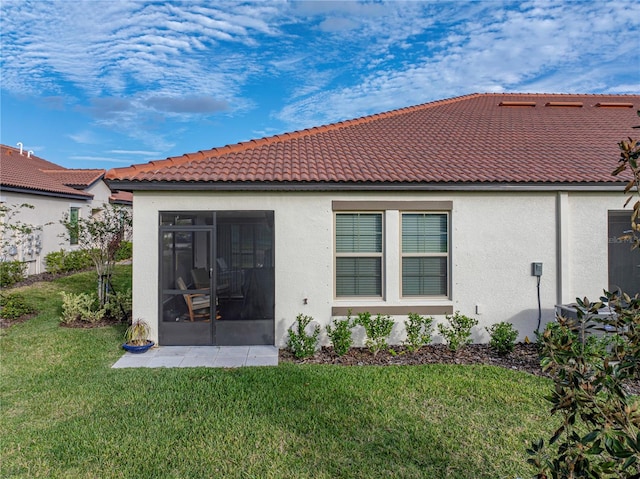 rear view of property featuring a sunroom and a lawn