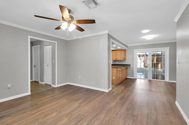 unfurnished living room with dark wood-type flooring, baseboards, visible vents, and ornamental molding