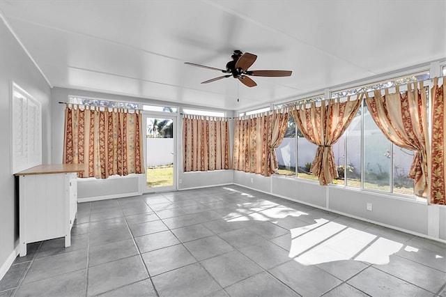 unfurnished room featuring a healthy amount of sunlight, tile patterned flooring, baseboards, and a ceiling fan