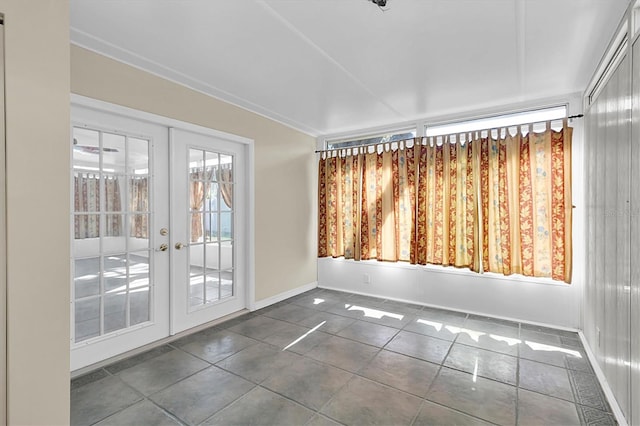 spare room featuring french doors, baseboards, and dark tile patterned flooring