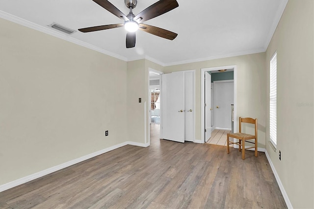 unfurnished bedroom featuring light wood-style floors, visible vents, ornamental molding, and baseboards