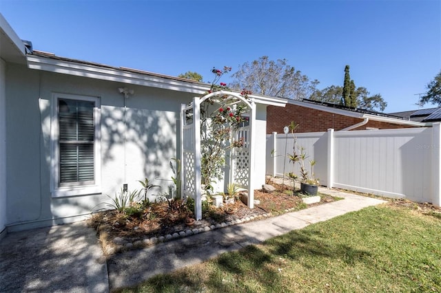 view of side of home featuring brick siding and fence