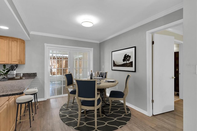 dining space featuring french doors, baseboards, wood finished floors, and ornamental molding