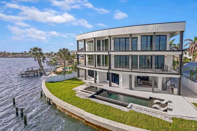 rear view of house with a pool with hot tub, a patio area, a water view, and a balcony