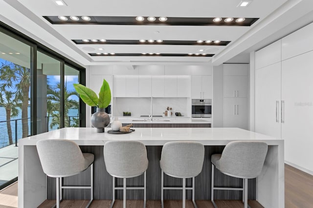 kitchen featuring a breakfast bar area, dark hardwood / wood-style flooring, white cabinets, and a spacious island