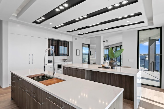 kitchen featuring a water view, a large island with sink, and light hardwood / wood-style flooring