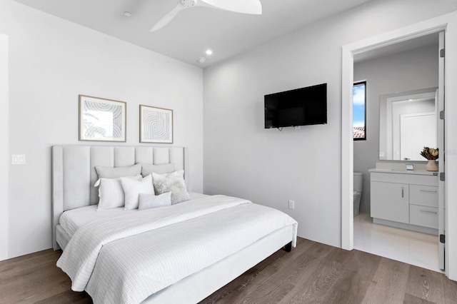 bedroom featuring dark hardwood / wood-style flooring, ensuite bath, and ceiling fan