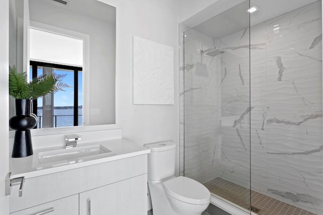 bathroom with vanity, toilet, a water view, and a tile shower