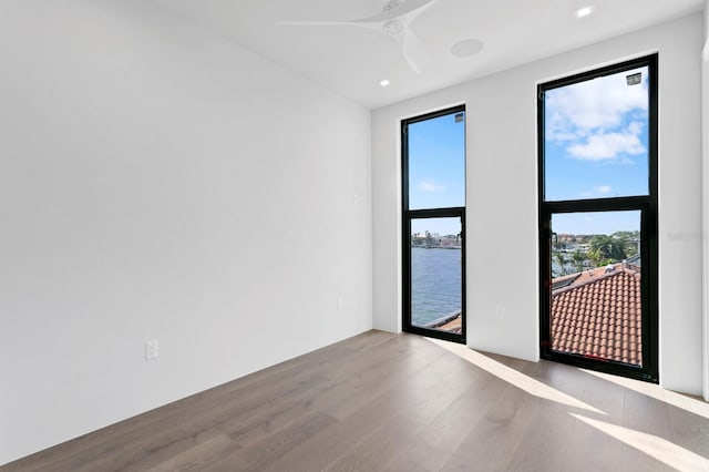 empty room with hardwood / wood-style floors, ceiling fan, and a water view