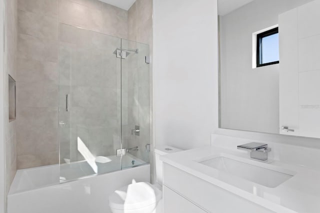 full bathroom featuring vanity, toilet, and shower / bath combination with glass door