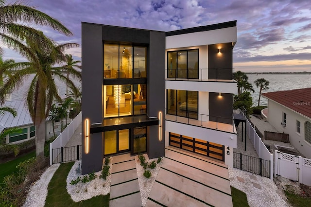 back house at dusk with a water view and a balcony