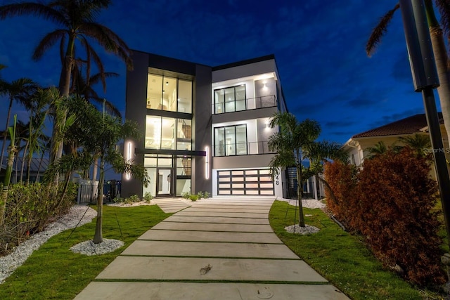 view of front of house featuring a lawn, a garage, and a balcony