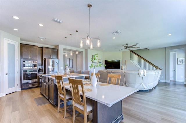 kitchen featuring a kitchen bar, a large island, hanging light fixtures, and light hardwood / wood-style floors