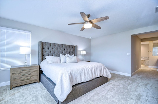 bedroom with connected bathroom, light colored carpet, and ceiling fan