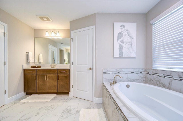 bathroom featuring tiled bath and vanity