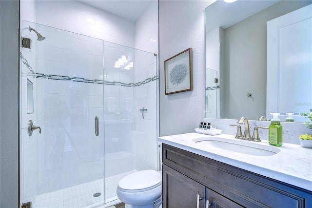 bathroom with vanity, a shower with shower door, and toilet