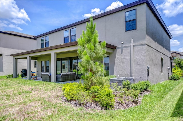 rear view of property with central AC unit, an outdoor living space, and a lawn