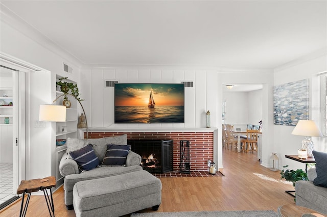 living room with ornamental molding, a fireplace, and light hardwood / wood-style flooring