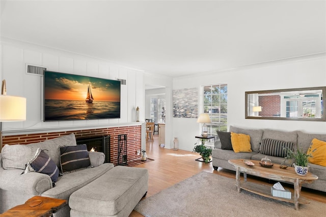 living room with a fireplace, light hardwood / wood-style floors, and ornamental molding