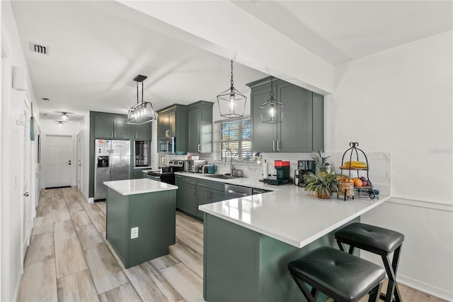 kitchen with sink, kitchen peninsula, hanging light fixtures, and appliances with stainless steel finishes