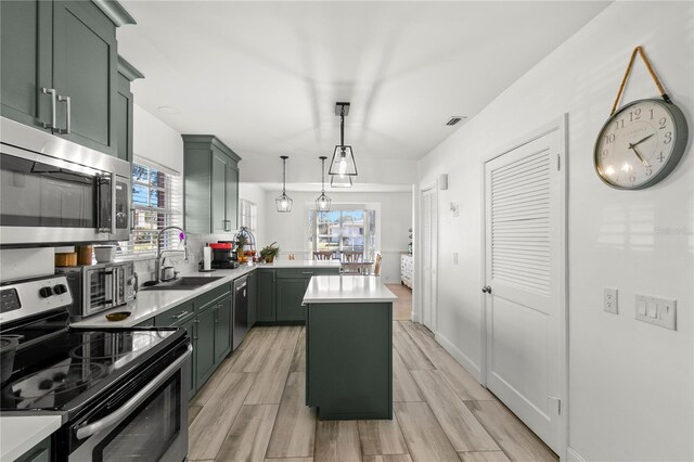 kitchen featuring appliances with stainless steel finishes, a center island, decorative light fixtures, and a wealth of natural light