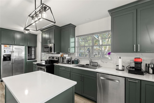 kitchen with appliances with stainless steel finishes, sink, pendant lighting, a center island, and green cabinets