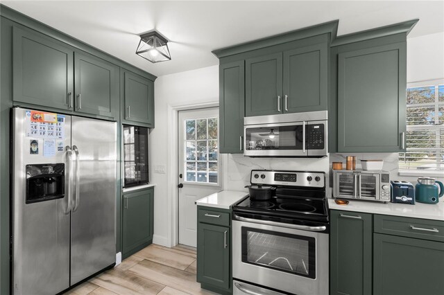 kitchen with a wealth of natural light, appliances with stainless steel finishes, and green cabinetry