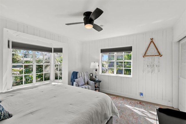 bedroom featuring wood-type flooring, ceiling fan, and wood walls