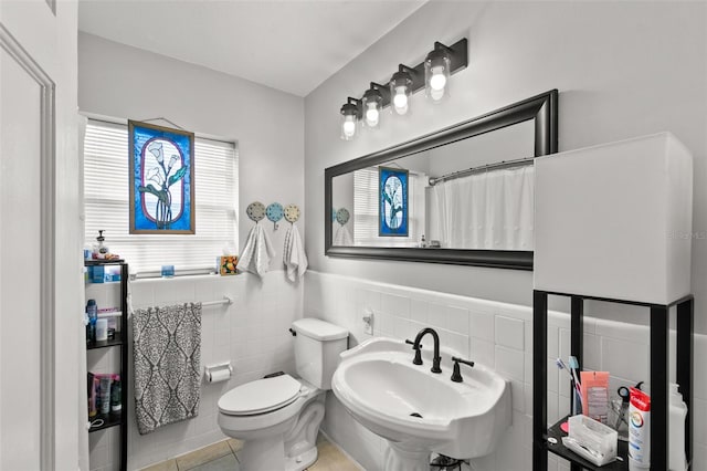 bathroom featuring sink, walk in shower, tile patterned floors, toilet, and tile walls