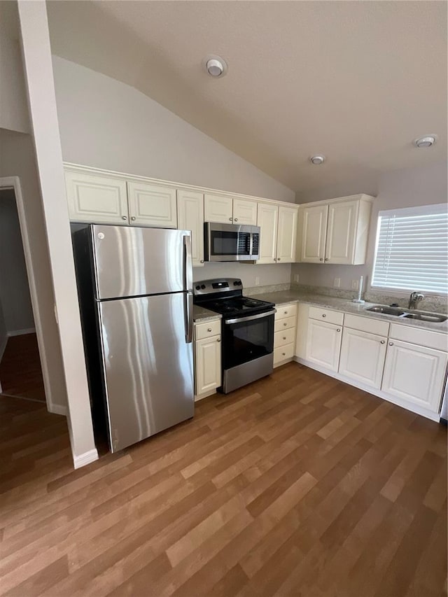 kitchen with sink, white cabinets, stainless steel appliances, and lofted ceiling