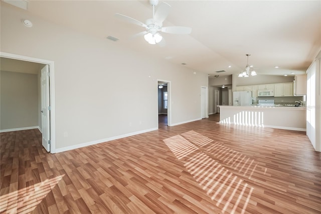 unfurnished living room featuring lofted ceiling, ceiling fan with notable chandelier, and light wood-type flooring