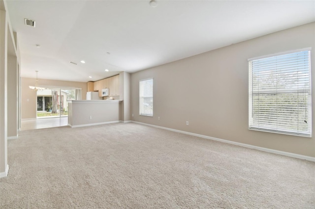 unfurnished living room featuring light colored carpet and plenty of natural light