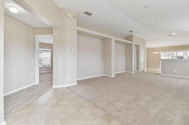 carpeted spare room with a notable chandelier