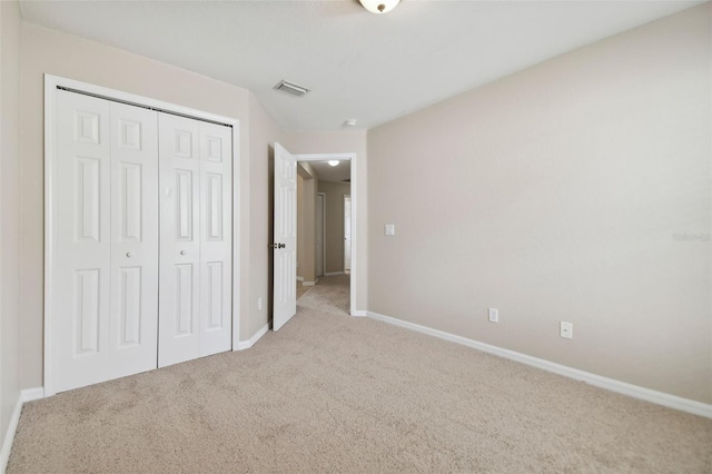 unfurnished bedroom featuring a closet and light colored carpet