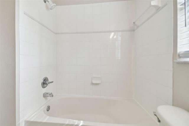 bathroom with toilet and tiled shower / bath