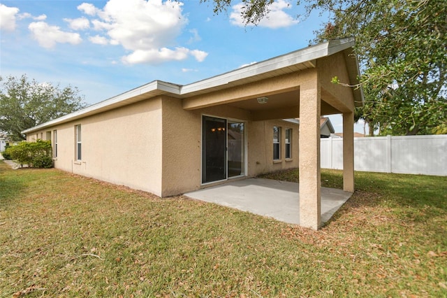 rear view of property featuring a lawn and a patio