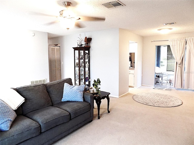 carpeted living room featuring ceiling fan and a textured ceiling