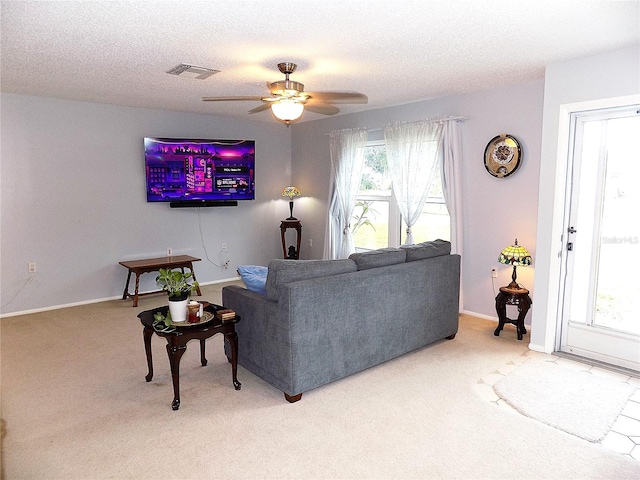 living room featuring ceiling fan, carpet floors, and a textured ceiling