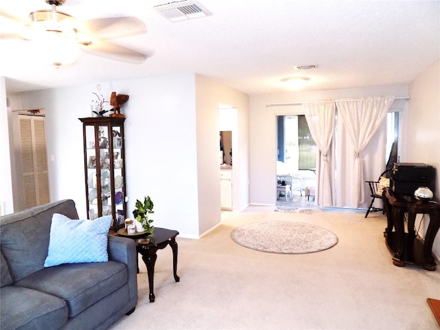 carpeted living room featuring ceiling fan and a textured ceiling